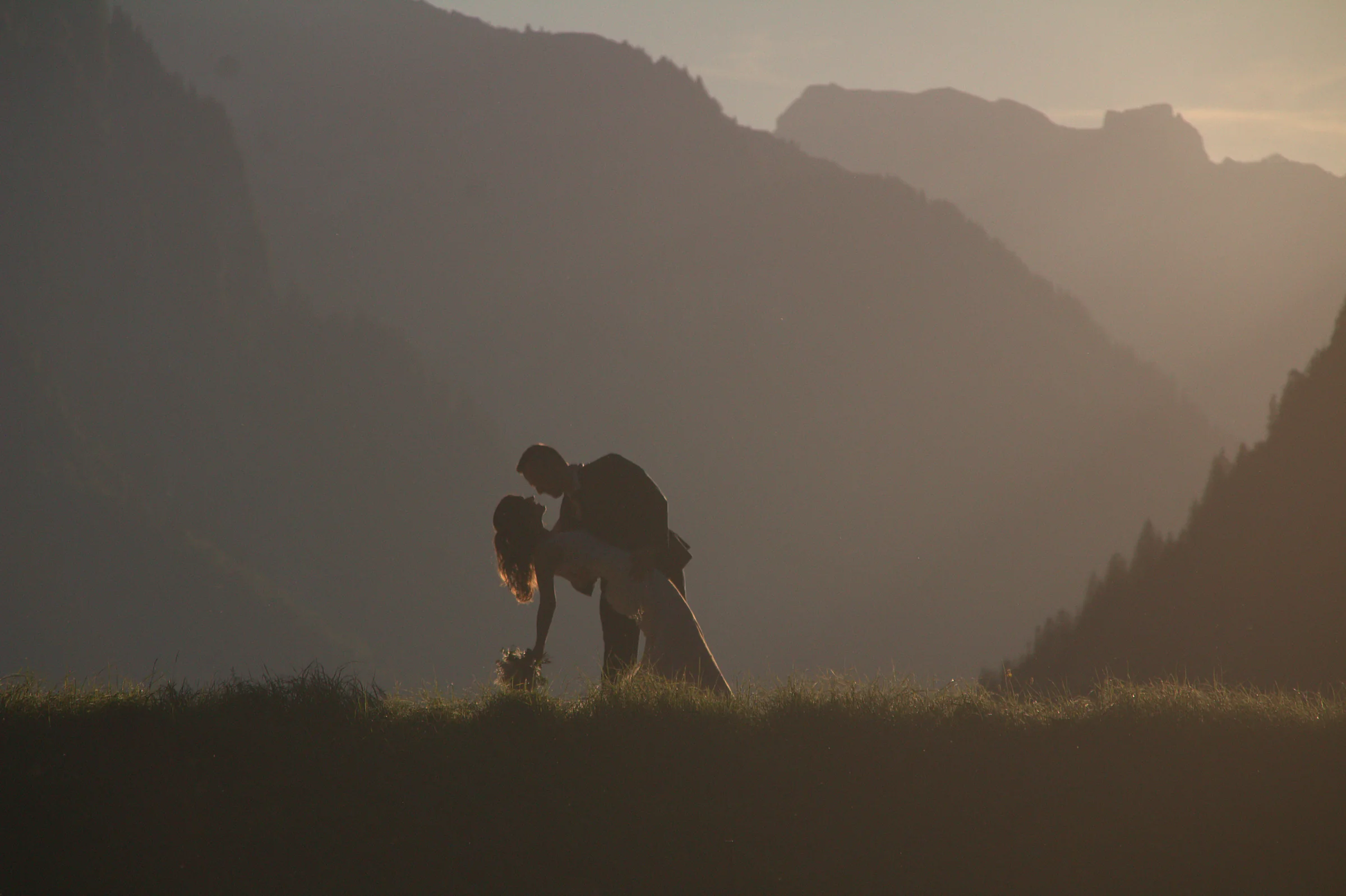 Brautpaar im Dip-Kuss als Silhouette vor Bergkulisse